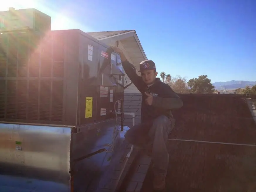 HVAC technician performing Air Duct Cleaning on a rooftop unit in Ludlow